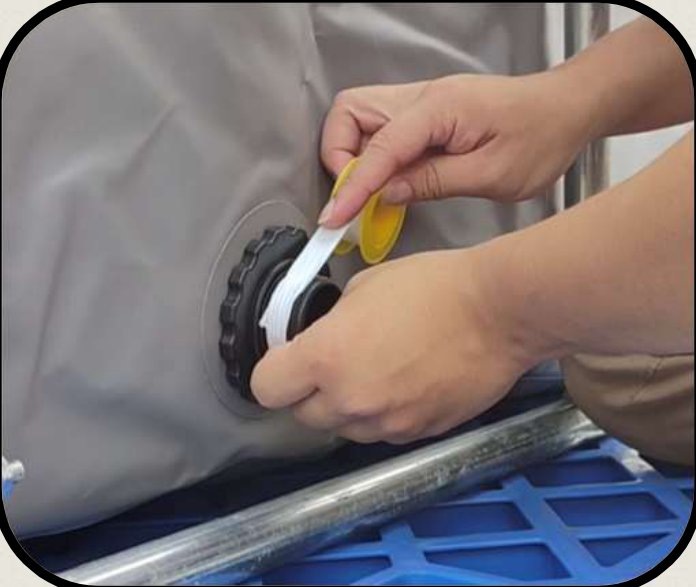 A hand wrapping white Teflon tape around the thread of the drainage port, with the tape roll held in the same hand.