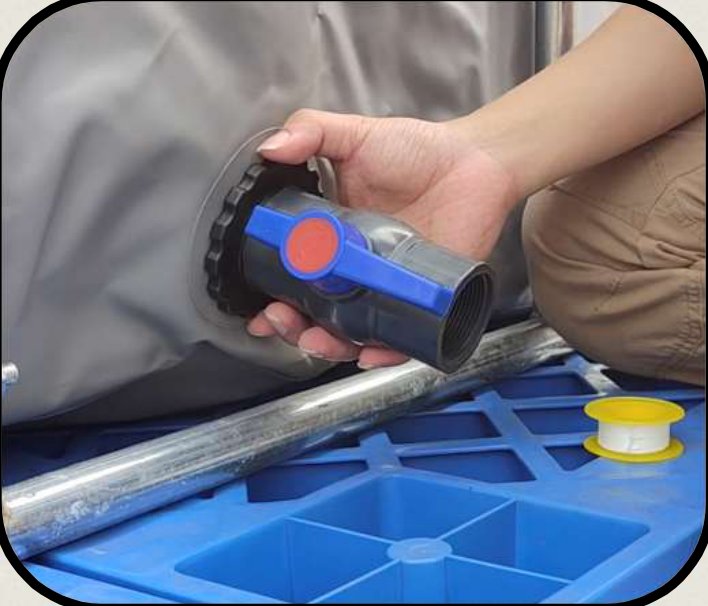 A hand holding the blue and grey PVC ball valve against the taped drainage port, ready to screw on.